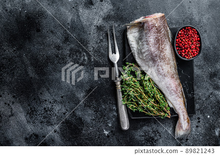 Uncooked Raw cod whole fish on marble board with thyme. Black background. Top view. Copy space 89821243