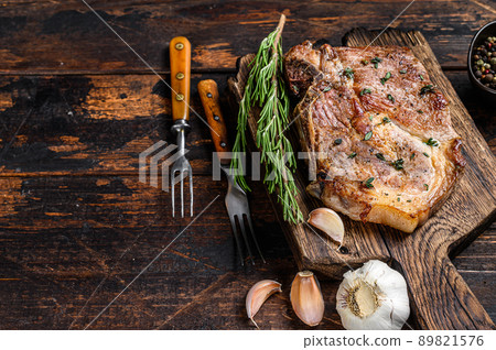 Roasted pork chop steak on a cutting board. Dark wooden background. Top view. Copy space 89821576