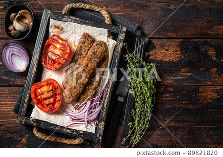 Turkish urfa kebab in a wooden tray with bread, onion and tomato. Wooden background. top view. Copy space 89821820