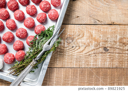 Recipe for cooking meatballs from ground beef with thyme and rosemary in kitchen tray. Wooden background. Top view. Copy space 89821925