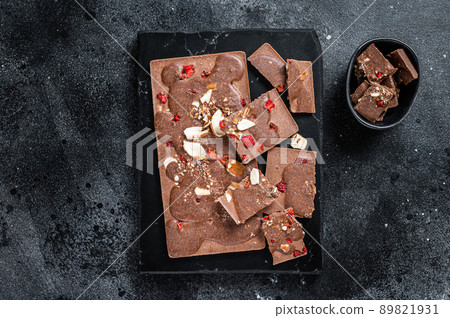 Craft homemade chocolate bars chopped on marble board. Black background. Top view Craft homemade chocolate bars chopped on marble board. Black background. Top view 89821931