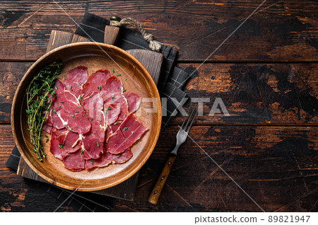 Pastrami slices, dried beef meat with herbs in wooden plate. Wooden background. Top view. Copy space 89821947