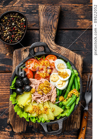 Nicoise salad with tuna, cherry tomatoes, olives, green beans, cucumber, soft boiled eggs and potato. Dark wooden background. top view 89822052