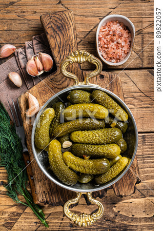 Pickled gherkins cucumbers in bowl with herbs. Wooden background. Top view Pickled gherkins cucumbers in bowl with herbs. Wooden background. Top view 89822057