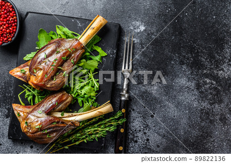 Stew goat Shanks on a marble board with arugula. Black background. Top view. Copy space 89822136