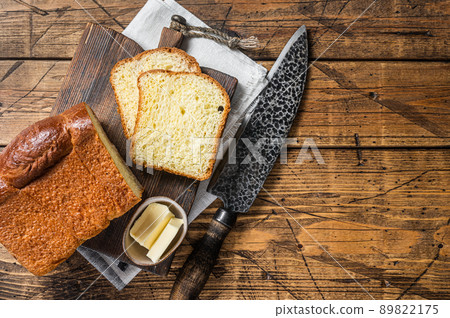 Baked sliced Brioche bread with butter. Wooden background. Top view. Copy space Baked sliced Brioche bread with butter. Wooden background. Top view. Copy space 89822175