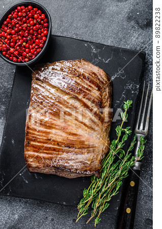 Grilled flank beef meat steak on a marble board. Black background. Top view 89822238