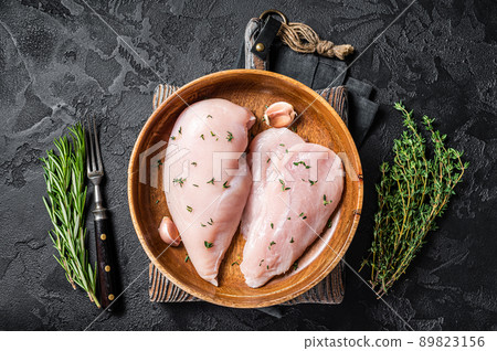Sliced raw Chicken breast fillet, poultry meat steaks in plate. Black background. Top view 89823156