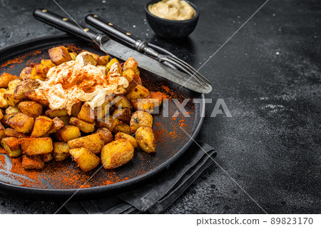 Patatas Bravas, traditional Spanish tapas, baked potato with spicy tomato sauce. Black background. Top view. Copy space Patatas Bravas, traditional Spanish tapas, baked potato with spicy tomato sauce. Black background. Top view. Copy space 89823170
