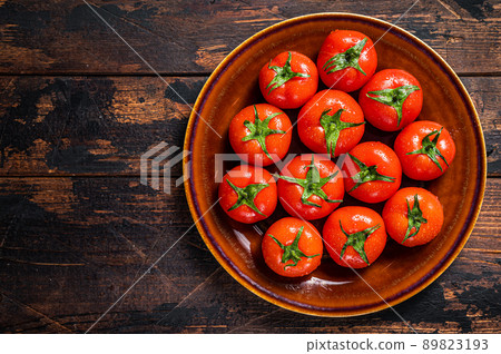 Red ripe tomatoes on rustic plate. Dark Wooden background. Top view. Copy space 89823193
