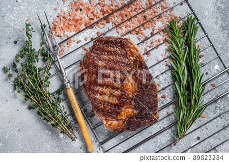 BBQ grilled rib-eye steak, rib eye beef meat on a grill with herbs. Gray background. top view BBQ grilled rib-eye steak, rib eye beef meat on a grill with herbs. Gray background. top view 89823284