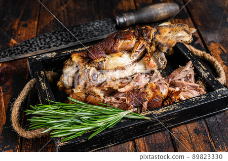 Roasted pork knuckle eisbein meat in a wooden tray with knife. Dark wooden background. Top view Roasted pork knuckle eisbein meat in a wooden tray with knife. Dark wooden background. Top view 89823330