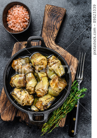 Canned artichokes in olive oil on a rustic wooden kitchen table. Black background. Top view 89823339