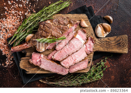 BBQ Grilled Tomahawk Steak, Rib eye on a wooden board. Dark background. Top view BBQ Grilled Tomahawk Steak, Rib eye on a wooden board. Dark background. Top view 89823364