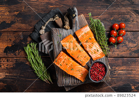 Raw Salmon fillet steaks on wooden board with thyme and rosemary. Wooden background. Top view 89823524