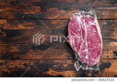 Raw dry aged beef round steak piece. Dark wooden background. Top view. Copy space 89823528