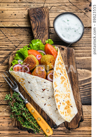Vegetarian Tortilla wrap with falafel and fresh salad, vegan tacos. wooden background. Top view Vegetarian Tortilla wrap with falafel and fresh salad, vegan tacos. wooden background. Top view 89823555