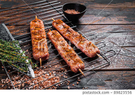 Uncooked Raw Urfa shish kebab on a grill with pink salt. Wooden background. top view. Copy space Uncooked Raw Urfa shish kebab on a grill with pink salt. Wooden background. top view. Copy space 89823556