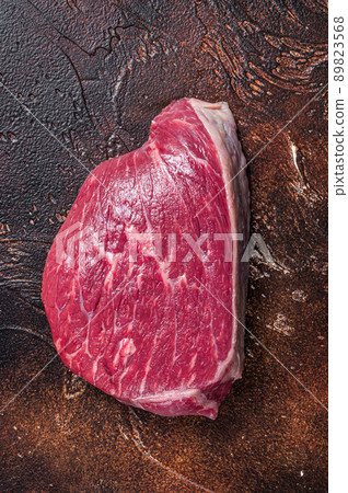 Raw rump beef cut or top sirloin meat steak on butcher table. Dark background. Top view Raw rump beef cut or top sirloin meat steak on butcher table. Dark background. Top view 89823568