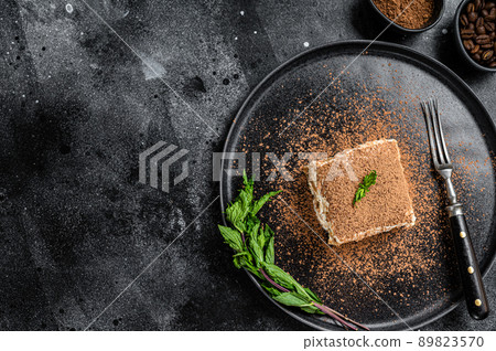 Italian Tiramisu cake with cocoa and mint on a plate. Black background. Top view. Copy space 89823570
