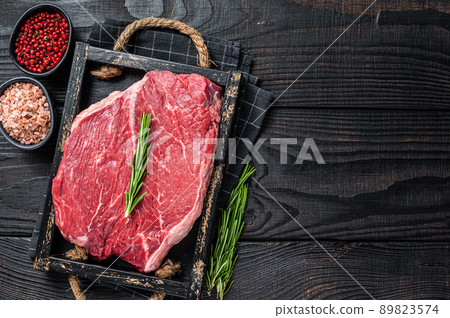 Beef raw fillet for steaks in a wooden tray with herbs. Black wooden background. Top view. Copy space Beef raw fillet for steaks in a wooden tray with herbs. Black wooden background. Top view. Copy space 89823574