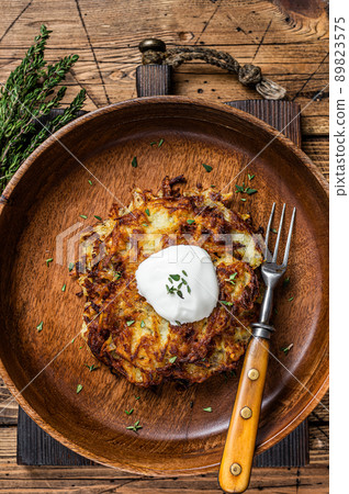 Roasted Potato pancakes or Fritters with herbs in a wooden plate. wooden background. Top view Roasted Potato pancakes or Fritters with herbs in a wooden plate. wooden background. Top view 89823575