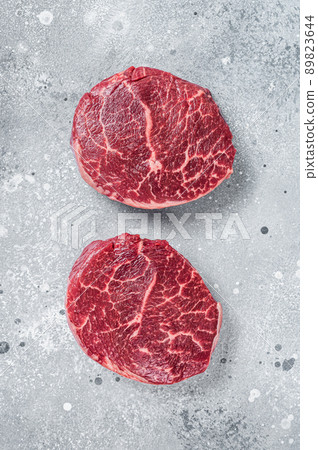 Raw fillet Mignon beef steaks on a butcher board. Gray background. Top view 89823644