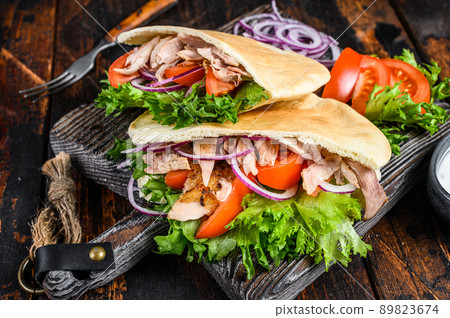 Greek gyros wrapped in pita breads with vegetables and sauce. Dark wooden background. Top view 89823674