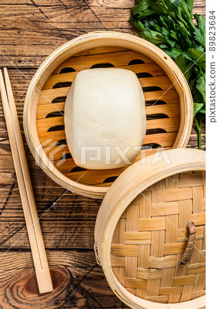 Chinese Steamed Buns in traditional bamboo steamer. Wooden background. Top view Chinese Steamed Buns in traditional bamboo steamer. Wooden background. Top view 89823684