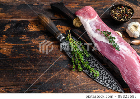 Raw fresh pork tenderloin meat on a cuuting board with cleaver. Dark wooden background. Top view. Copy space Raw fresh pork tenderloin meat on a cuuting board with cleaver. Dark wooden background. Top view. Copy space 89823685
