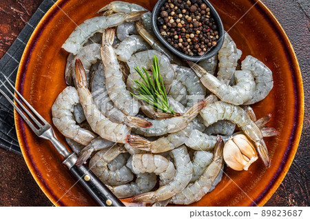 Black Raw uncooked Headless giant shrimps prawns in a rustic plate. Dark background. Top view Black Raw uncooked Headless giant shrimps prawns in a rustic plate. Dark background. Top view 89823687