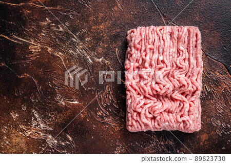 Raw ground chicken or turkey meat on brown table. Dark background. Top View. Copy space Raw ground chicken or turkey meat on brown table. Dark background. Top View. Copy space 89823730
