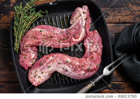 Raw Tenderloin pork fillet ready for cooking, uncooked meat in grill pan with herbs and olive oil. Wooden background. Top view Raw Tenderloin pork fillet ready for cooking, uncooked meat in grill pan with herbs and olive oil. Wooden background. Top view 89823780