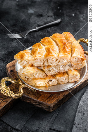 Traditional feta cheese phyllo pastry pie in rustic skillet. Black background. Top view 89823806