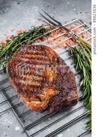 BBQ grilled rib-eye steak, rib eye beef meat on a grill with herbs. Gray background. top view 89823836