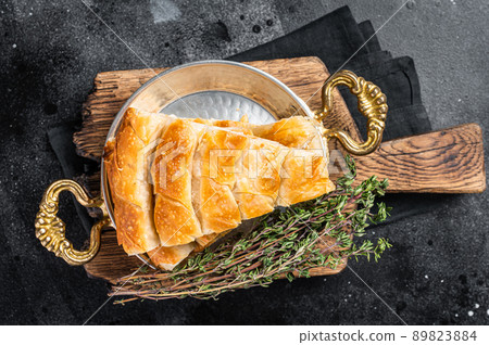 Traditional feta cheese phyllo pastry pie in rustic skillet. Black background. Top view Traditional feta cheese phyllo pastry pie in rustic skillet. Black background. Top view 89823884