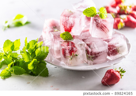 Frozen strawberries in ice cubes on a plate. Frozen strawberries in ice cubes on a plate. 89824165