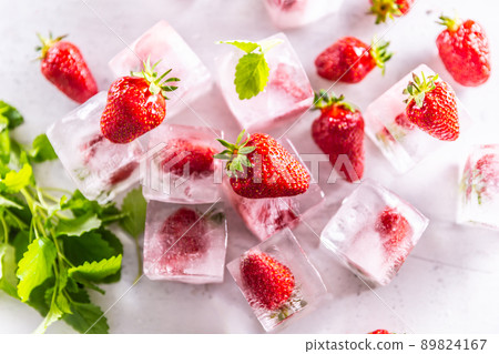 Strawberries frozen in ice cubes with mellisa leaves - Top of view. Strawberries frozen in ice cubes with mellisa leaves - Top of view. 89824167