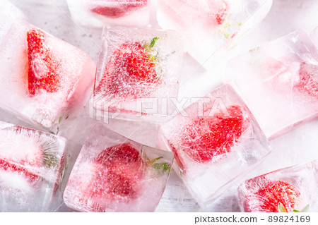 Strawberries frozen in ice cubes - Top of view. Strawberries frozen in ice cubes - Top of view. 89824169