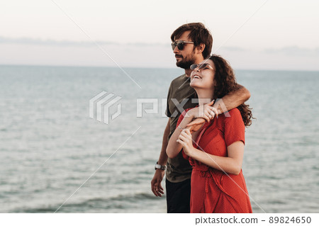 Portrait of Young Couple on the Background of Sea, Happy Man Hugging Curly Woman in Red Dress at Sunset Portrait of Young Couple on the Background of Sea, Happy Man Hugging Curly Woman in Red Dress at Sunset 89824650