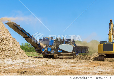 An industrial wood chipper at work with roots for grinding machine to become chip 89824693