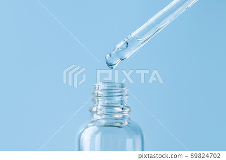 Pipette with transparent fluid hyaluronic acid or serum. Cosmetics, science and healthcare concept closeup. Dose of serum or retinol falls in a bottle. Front view. Beauty product presentation, macro 89824702
