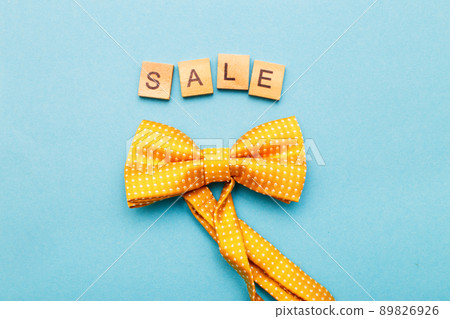 the word sale made by wooden cubes on a blue background with a yellow bow tie. the word sale made by wooden cubes on a blue background with a yellow bow tie. 89826926