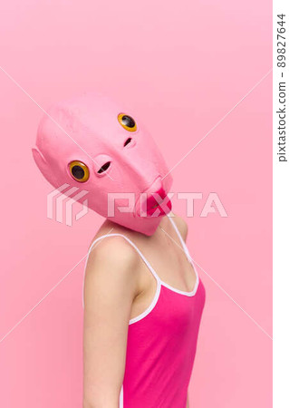 Modern Halloween costume in a silicone mask in the shape of a pink fish head in a sexy costume. The concept of a crazy look Modern Halloween costume in a silicone mask in the shape of a pink fish head in a sexy costume. The concept of a crazy look 89827644