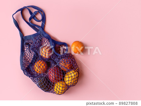 Net bag with fruit on bright background. Zero waste and ecology conservation concept. Fresh apples, tangerines, avocado and pomegranate in a reusable eco friendly shopping bag Net bag with fruit on bright background. Zero waste and ecology conservation concept. Fresh apples, tangerines, avocado and pomegranate in a reusable eco friendly shopping bag 89827808