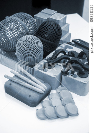 Many different models printed on 3D printer. Gray and black objects printed on 3D printer made of plastic close-up. Lots of 3D printed models. Prototypes of various shapes made by 3d printer on table. Many different models printed on 3D printer. Gray and black objects printed on 3D printer made of plastic close-up. Lots of 3D printed models. Prototypes of various shapes made by 3d printer on table. 89828133