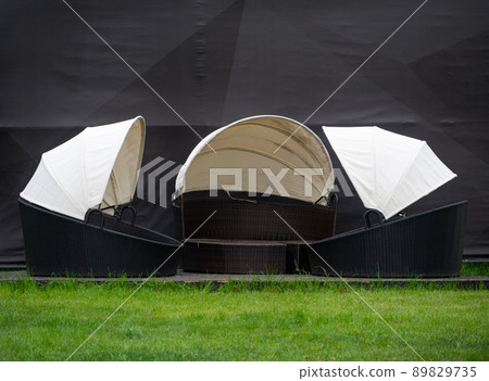 Outdoor sun beds on green grass, beach rattan chaise lounges, round wicker patio day bed. Outside backyard furniture. 89829735