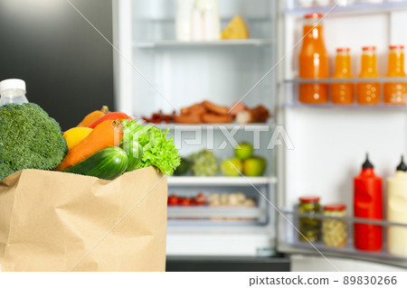 Paper bag full of products near refrigerator, closeup Paper bag full of products near refrigerator, closeup 89830266