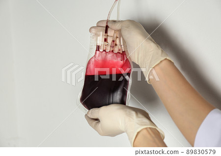 Woman holding blood for transfusion on light background, closeup. Donation concept Woman holding blood for transfusion on light background, closeup. Donation concept 89830579