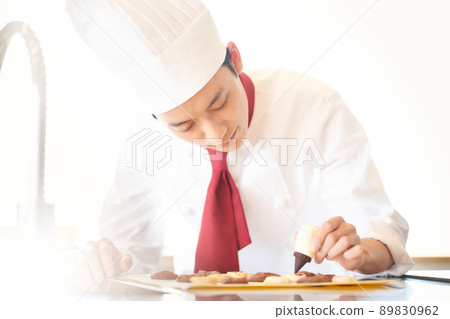 A young confectioner who pipes with chocolate 89830962